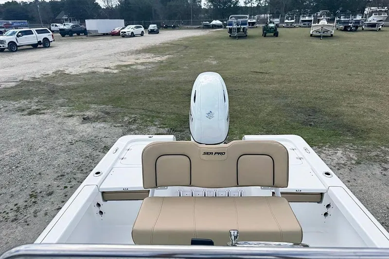 Slide: The Image of 2026 Sea Pro 230 Bay boat with beige seating and outboard motor in a parking area. - 29