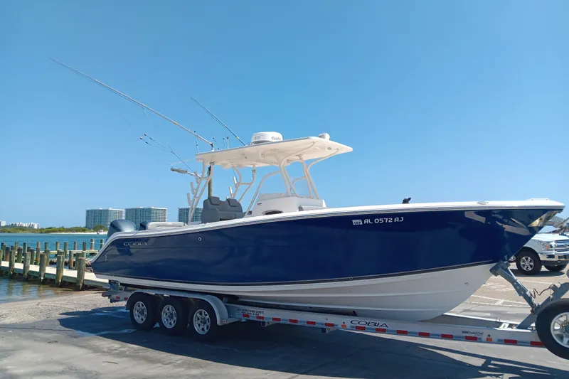 The Image of 2014 Cobia 296 Center Console boat on trailer, parked on grass. - 0