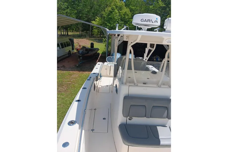 Slide: The Image of 2014 Cobia 296 Center Console boat docked outdoors, featuring spacious seating and modern equipment. - 15