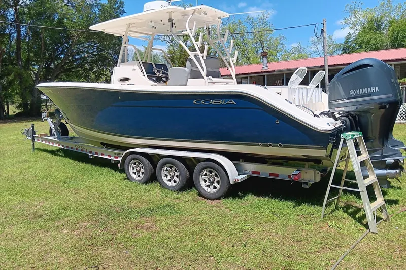 Slide: The Image of 2014 Cobia 296 Center Console boat on trailer with Yamaha engine, parked on grass. - 17
