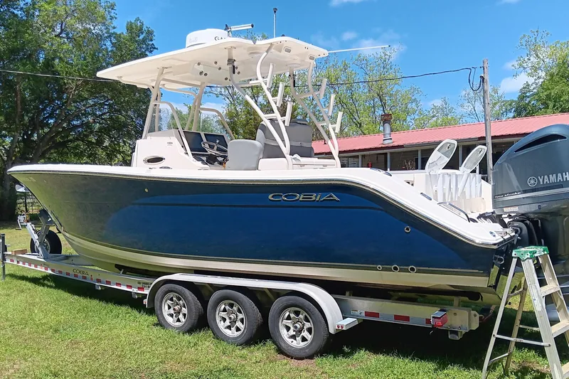 Slide: The Image of 2014 Cobia 296 Center Console boat on trailer, parked outdoors. - 18