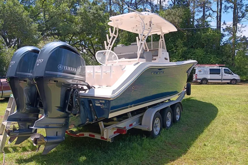 Slide: The Image of 2014 Cobia 296 Center Console boat with dual Yamaha engines on a trailer. - 19