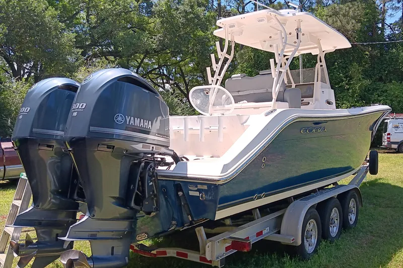 Slide: The Image of 2014 Cobia 296 Center Console boat with twin Yamaha engines on a trailer. - 20