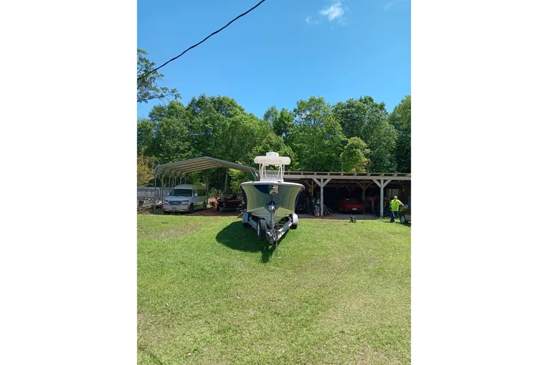 Slide: The Image of 2014 Cobia 296 Center Console boat on grassy yard with trees and carport. - 21