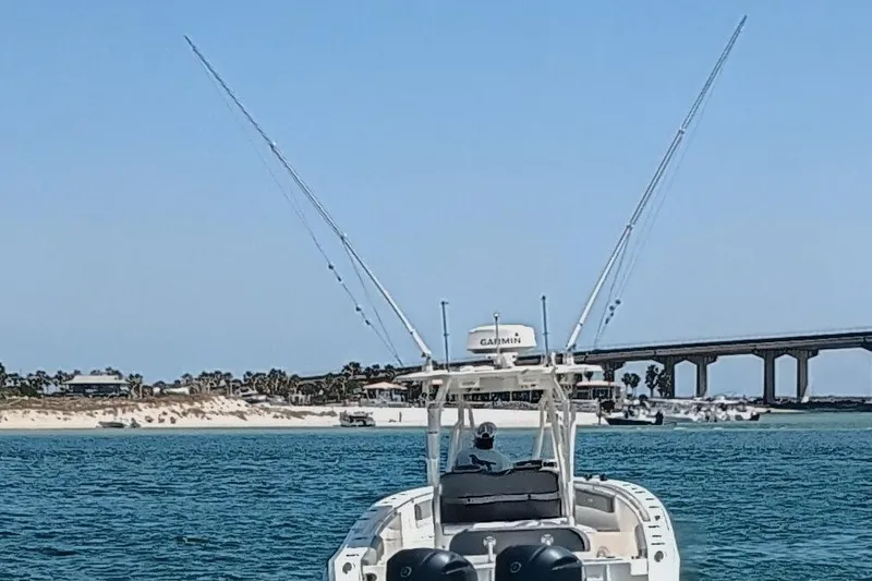 Slide: The Image of 2014 Cobia 296 Center Console boat on water near a bridge and sandy shoreline. - 25