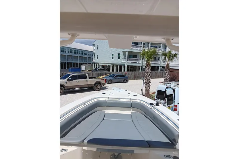 Slide: The Image of 2014 Cobia 296 Center Console boat with seating, parked near buildings and palm trees. - 34