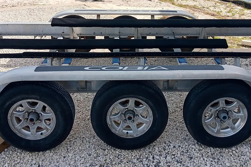 Slide: The Image of Triple-axle trailer for 2014 Cobia 296 Center Console boat on gravel surface. - 35