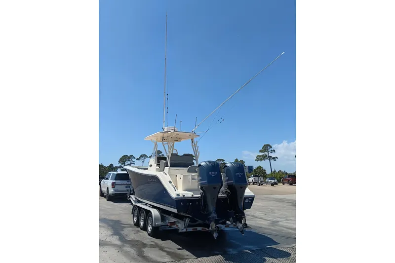 Slide: The Image of 2014 Cobia 296 Center Console boat on trailer with dual engines, parked outdoors. - 42
