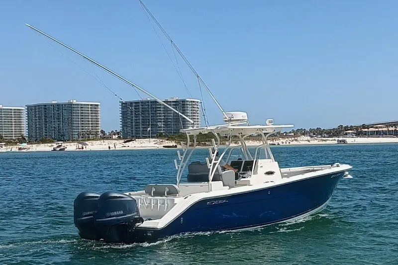 Slide: The Image of 2014 Cobia 296 Center Console boat cruising near beachfront buildings. - 43
