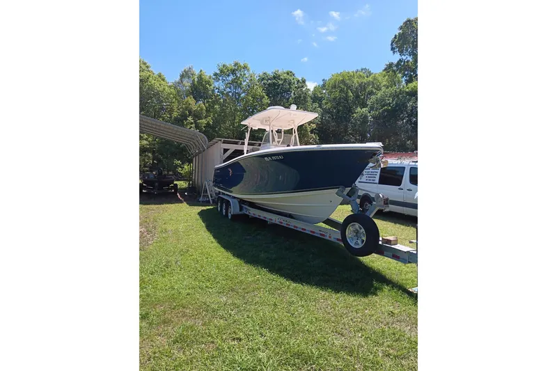 Slide: The Image of 2014 Cobia 296 Center Console boat on trailer, parked on grass with trees in background. - 5