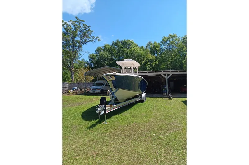 Slide: The Image of 2014 Cobia 296 Center Console boat on trailer, parked on grass near trees and a carport. - 6