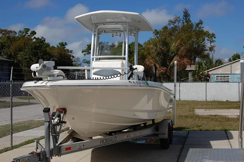 The Image of 2019 Robalo 226 Cayman boat on trailer, parked outdoors, clear sky background. - 1
