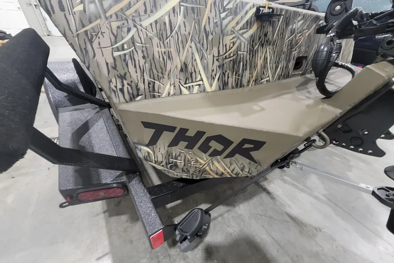 Slide: The Image of 2026 Thor 1860 Timber Hammer Elite boat with camouflage design on a trailer. - 6