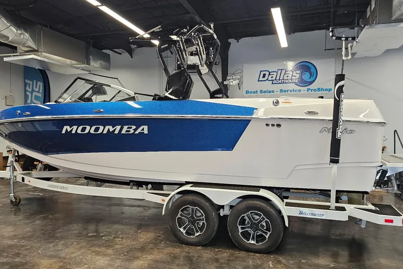 Slide: The Image of 2024 Moomba Mojo boat in showroom, blue and white design, on trailer. - 1