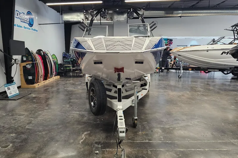 Slide: The Image of 2024 Moomba Mojo boat on trailer in showroom with surfboards displayed. - 4
