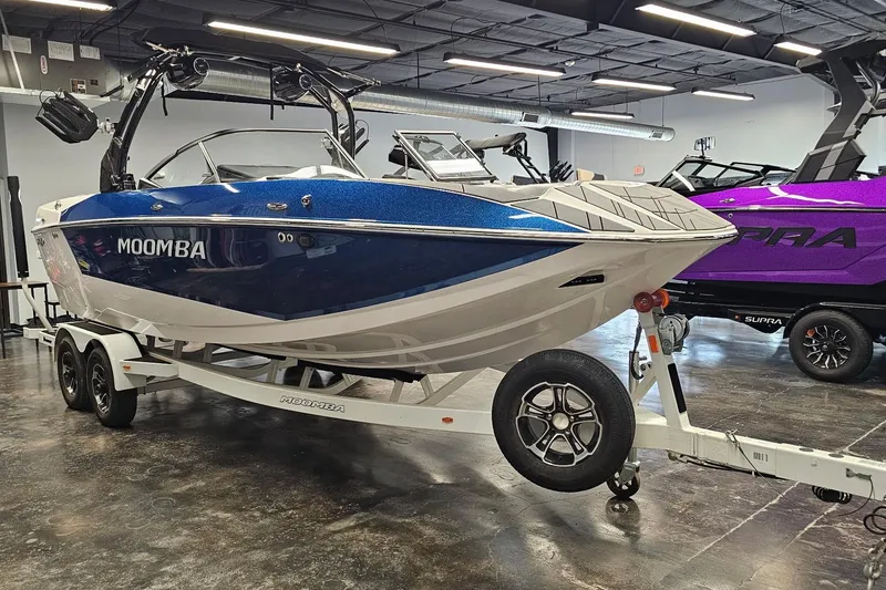 Slide: The Image of 2024 Moomba Mojo boat on trailer in showroom, blue and white design. - 5