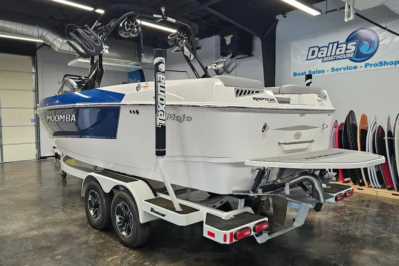 Slide: The Image of 2024 Moomba Mojo boat in showroom, featuring sleek design and dual-axle trailer. - 8