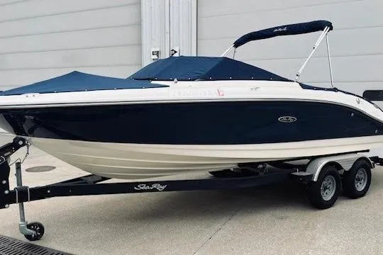 The Image of 2019 Sea Ray SPX 210 boat on trailer, navy blue hull, covered, parked outdoors. - 0