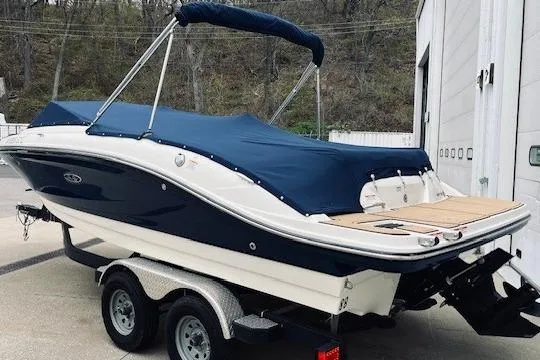 Slide: The Image of 2019 Sea Ray SPX 210 boat on trailer with blue cover, parked outdoors. - 2