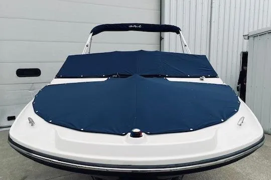 Slide: The Image of 2019 Sea Ray SPX 210 boat with blue cover, parked near a white building. - 3