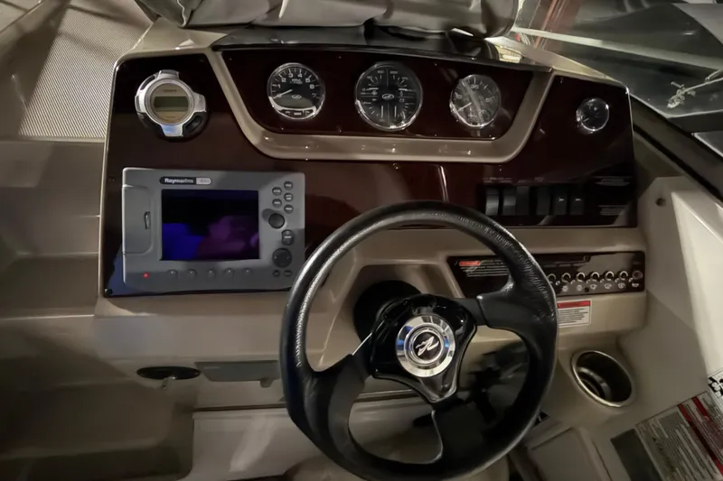 Slide: The Image of 2009 Sea Ray 270 Sundancer dashboard with steering wheel and navigation controls. - 10