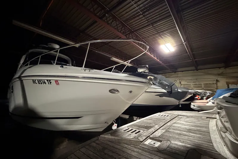Slide: The Image of 2009 Sea Ray 270 Sundancer boat stored indoors, docked alongside other vessels. - 8