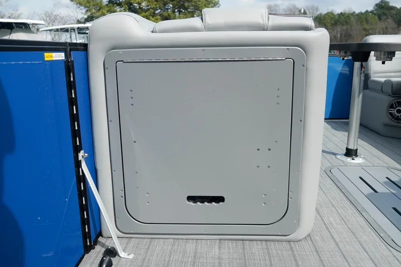 Slide: The Image of 2025 SunCatcher Fusion 324RCX boat interior with gray storage compartment and blue accents. - 23