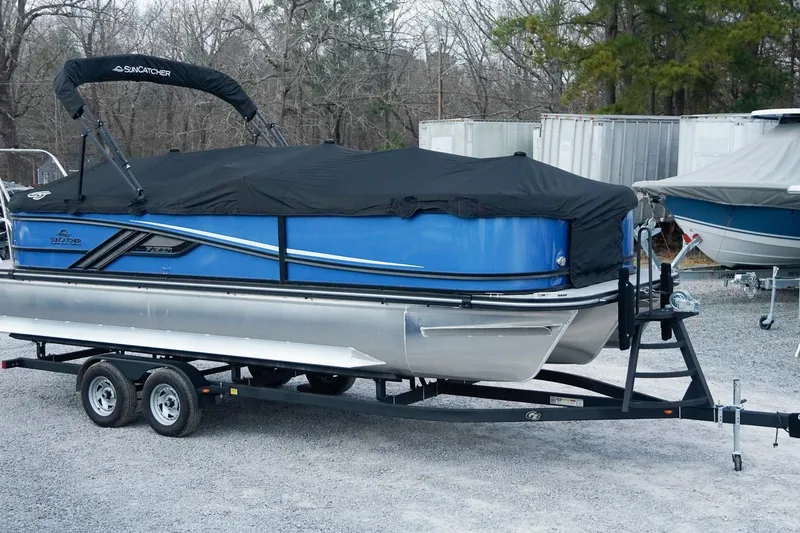 Slide: The Image of 2025 SunCatcher Fusion 324RCX pontoon boat on trailer, covered, in storage lot. - 4