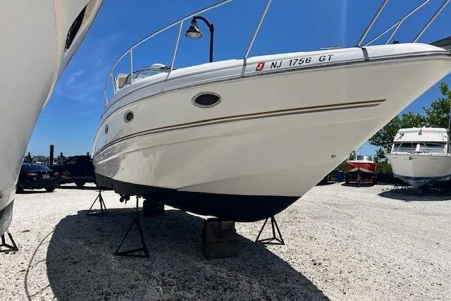 Slide: The Image of 2004 Larson 330 boat on stands in a sunny outdoor storage area. - 3