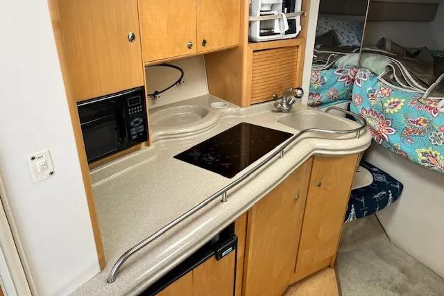 Slide: The Image of 2004 Larson 330 boat interior kitchen with stove, microwave, and cozy sleeping area. - 4