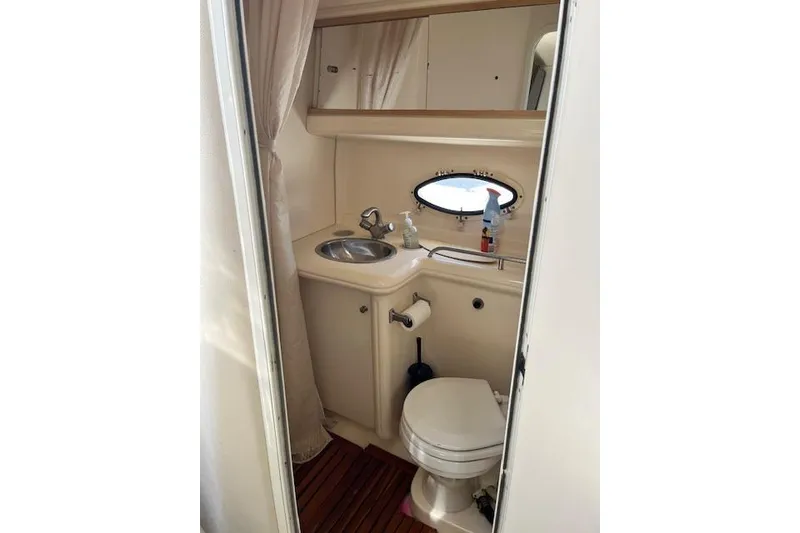 Slide: The Image of 2004 Larson 330 boat bathroom with sink, toilet, and oval window. - 6