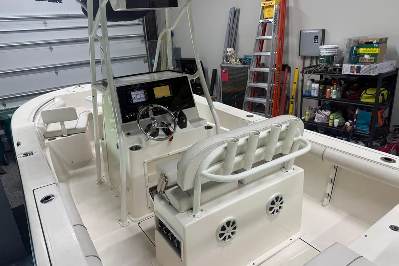 Slide: The Image of 2021 Seaborn LX22 boat interior with steering console, rod holders, and storage in a garage. - 8