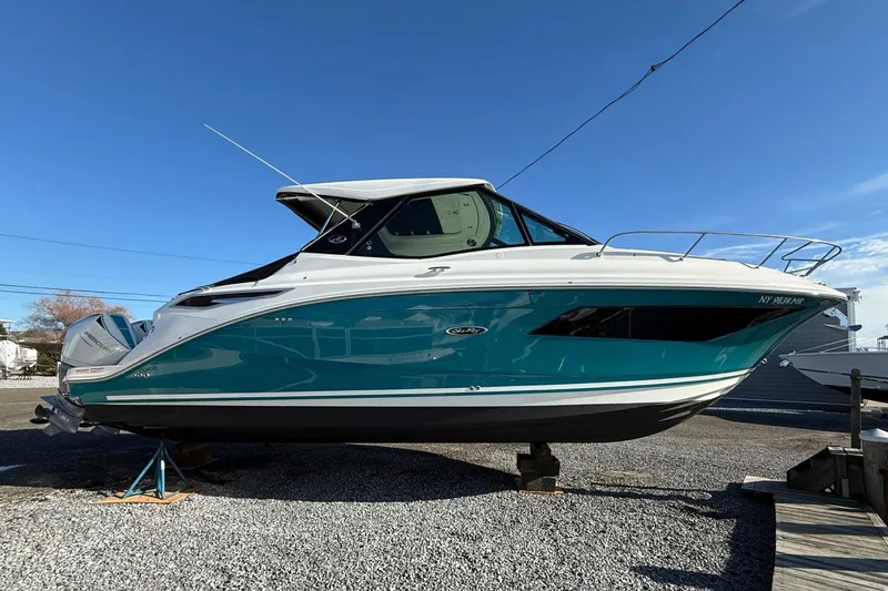 The Image of 2021 Sea Ray Sundancer 320 Coupe Outboard on display, vibrant blue hull, clear sky background. - 1