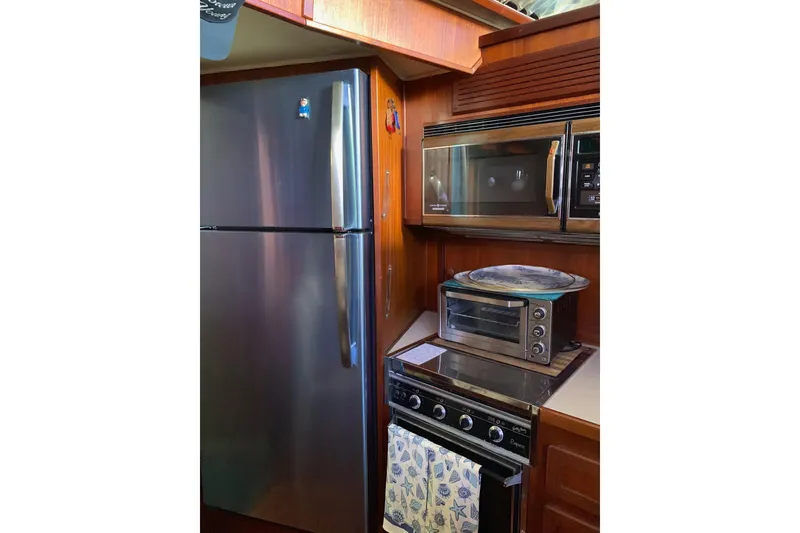 Slide: The Image of 1985 Chris-Craft 426 Catalina kitchen with stainless steel appliances and wooden cabinetry. - 24