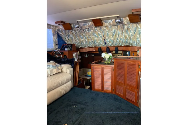 Slide: The Image of 1985 Chris-Craft 426 Catalina boat interior in a covered dock, featuring seating and blue cover. - 7