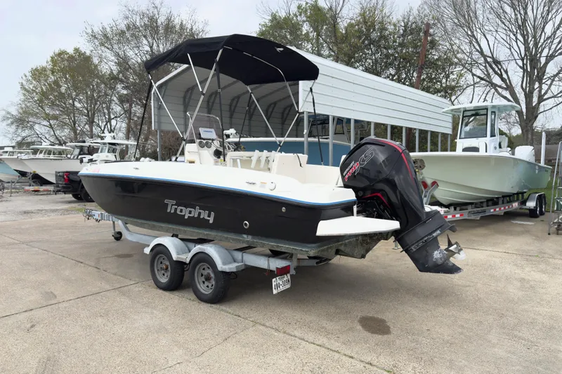 Slide: The Image of 2022 Bayliner Trophy T21Bay boat on trailer with outboard motor, parked outdoors. - 2