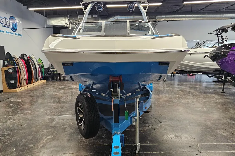 Slide: The Image of 2026 Moomba Max boat on trailer in showroom, surrounded by surfboards. - 3