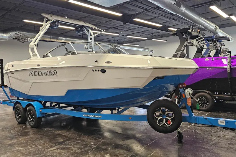 Slide: The Image of 2026 Moomba Max boat on trailer in showroom, featuring sleek design and vibrant blue accents. - 4