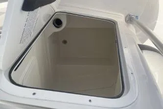 Slide: The Image of 2023 Sailfish 220 CC boat storage compartment, open lid, white interior. - 12