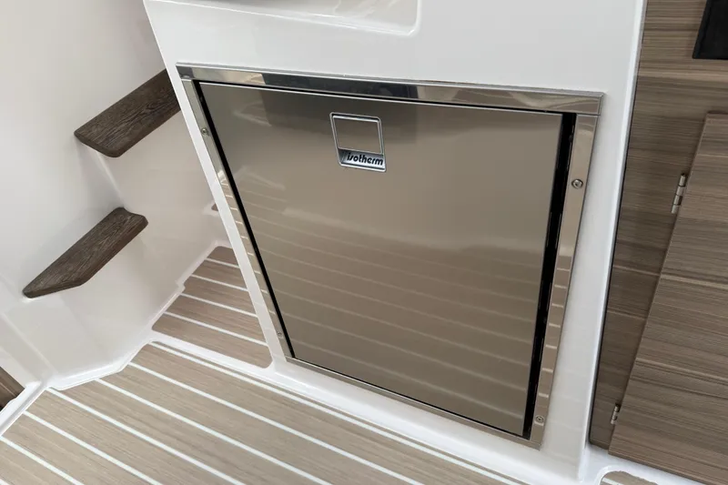 Slide: The Image of Stainless steel fridge in 2024 Solara S-250 Coupe boat interior with wood accents. - 27