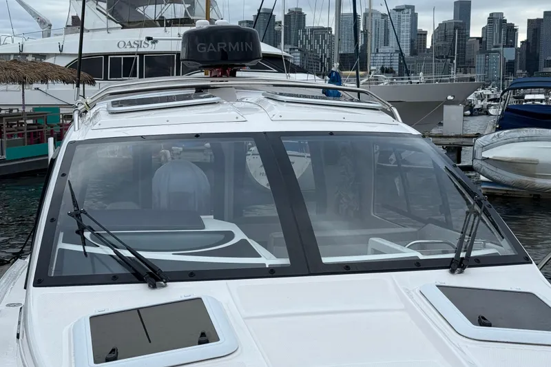 Slide: The Image of 2024 Solara S-250 Coupe boat docked at marina with city skyline in background. - 56