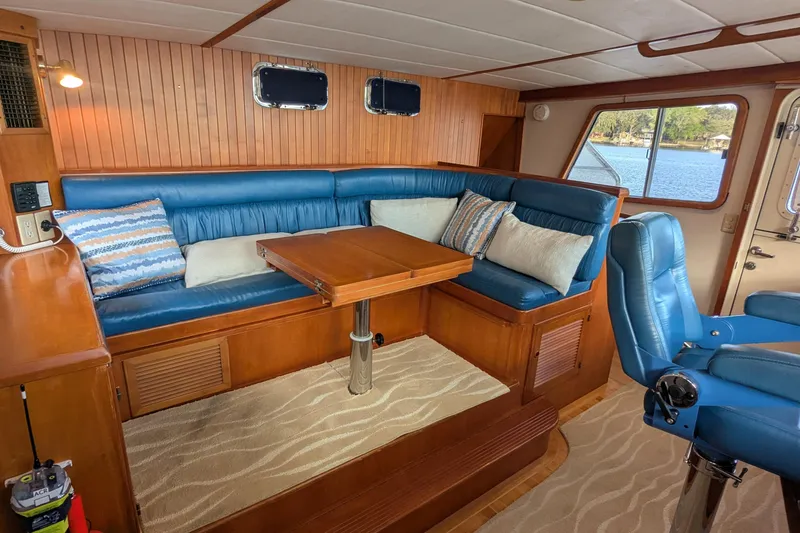 Slide: The Image of 2005 Kadey-Krogen Pilothouse interior with blue seating, wooden table, and scenic window view. - 103