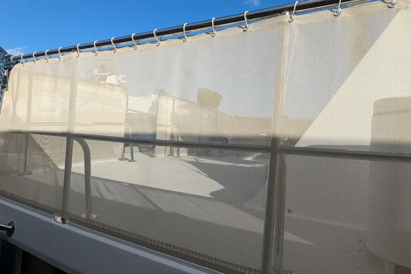 Slide: The Image of 2005 Kadey-Krogen Pilothouse boat with beige mesh railing under clear blue sky. - 12