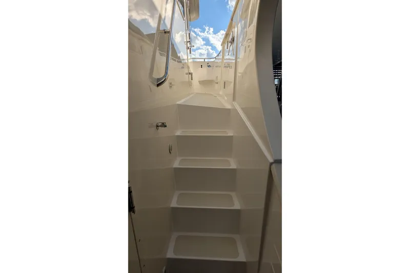 Slide: The Image of Staircase on 2005 Kadey-Krogen Pilothouse yacht, leading to upper deck under blue sky. - 21