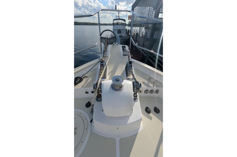 Slide: The Image of 2005 Kadey-Krogen Pilothouse boat deck with anchor chain and winch, docked by calm water. - 27