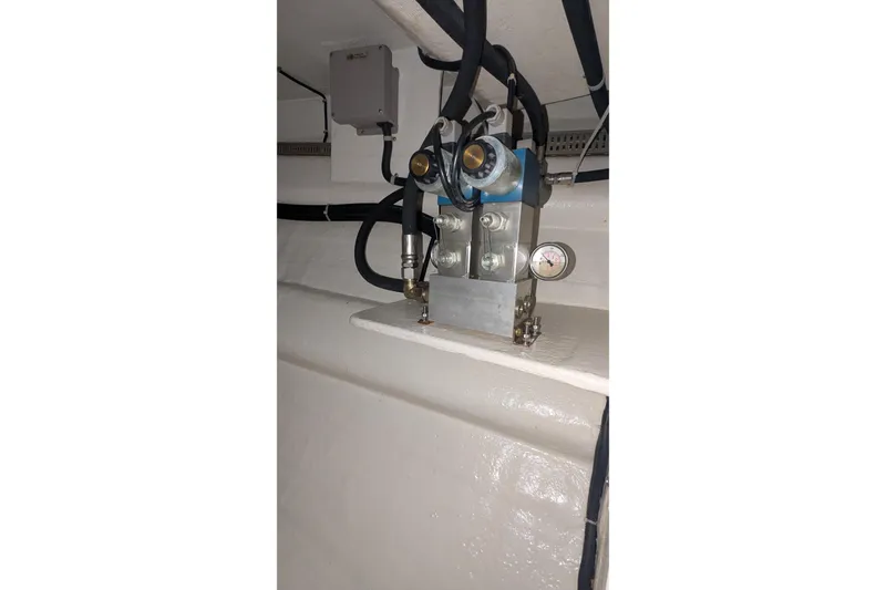 Slide: The Image of Engine room component in a 2005 Kadey-Krogen Pilothouse boat, featuring hoses and a pressure gauge. - 90