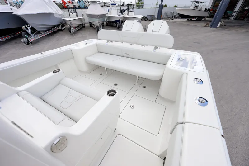 Slide: The Image of 2021 SeaVee 322Z boat interior with white seating and cup holders in a showroom. - 9