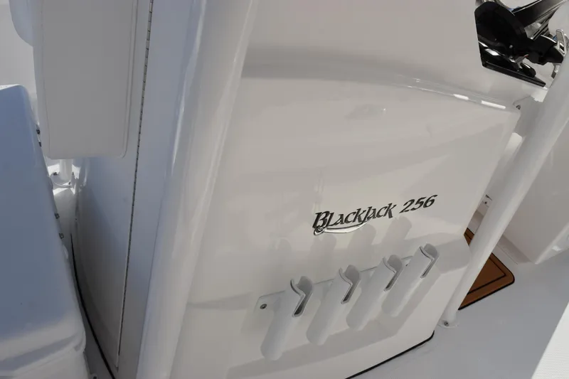 Slide: The Image of 2026 BlackJack 256 Coastal boat interior with rod holders and branding. - 15