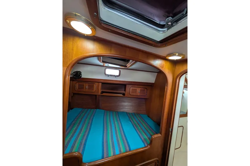 Slide: The Image of Cozy cabin interior of 1994 Passport Royal Passport 44 yacht with wooden finish and striped bedding. - 25