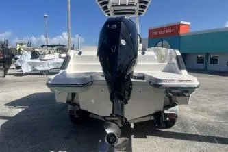 Slide: The Image of 2023 Trophy T24 CC boat with outboard motor, parked outdoors under clear blue sky. - 6